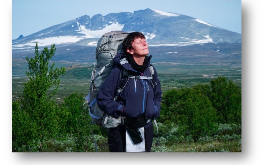Anne Grimstad Fjeld står og nyter naturens ro. I bakgrunnen ser du den norske fjellheimen.